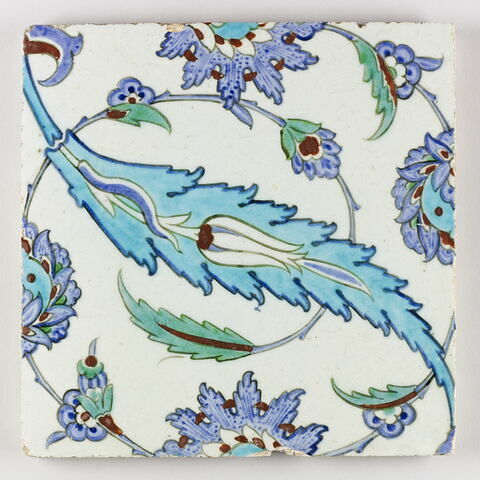 Carreau aux palmettes feuillues, aux feuilles dentelées enfermant une tulipe et aux fleurs épanouies saz
